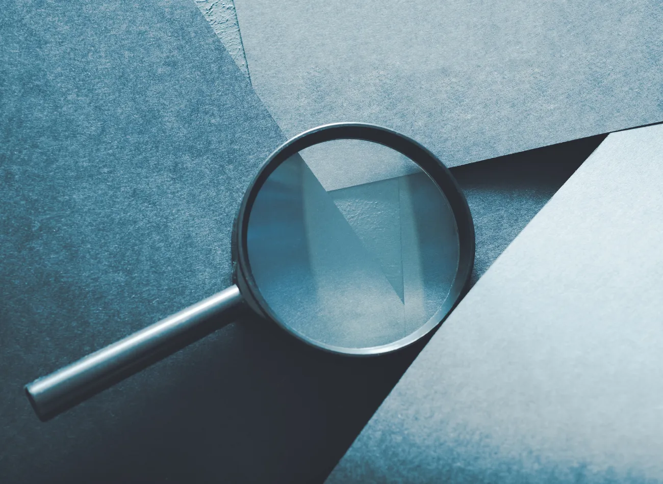 A magnifying glass resting on layered paper