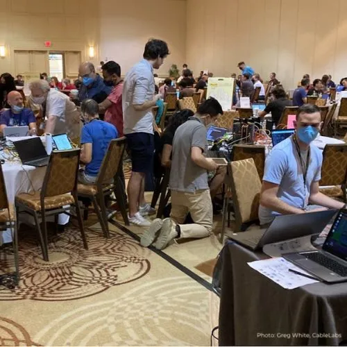 A crowded hotel ballroom of participants working at laptops (photo: Greg White, CableLabs)