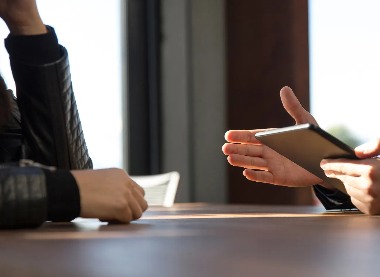 Two people discussing something on a smartphone across a table