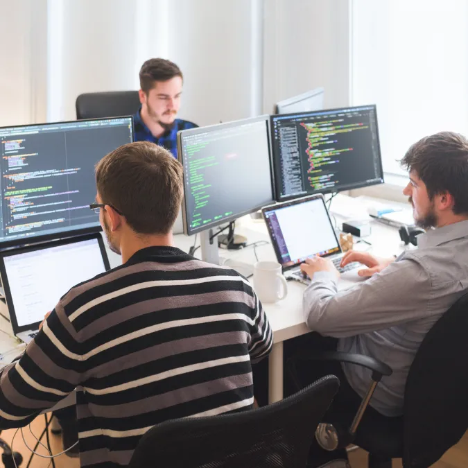 Developers working at multi-monitor workstations in an office