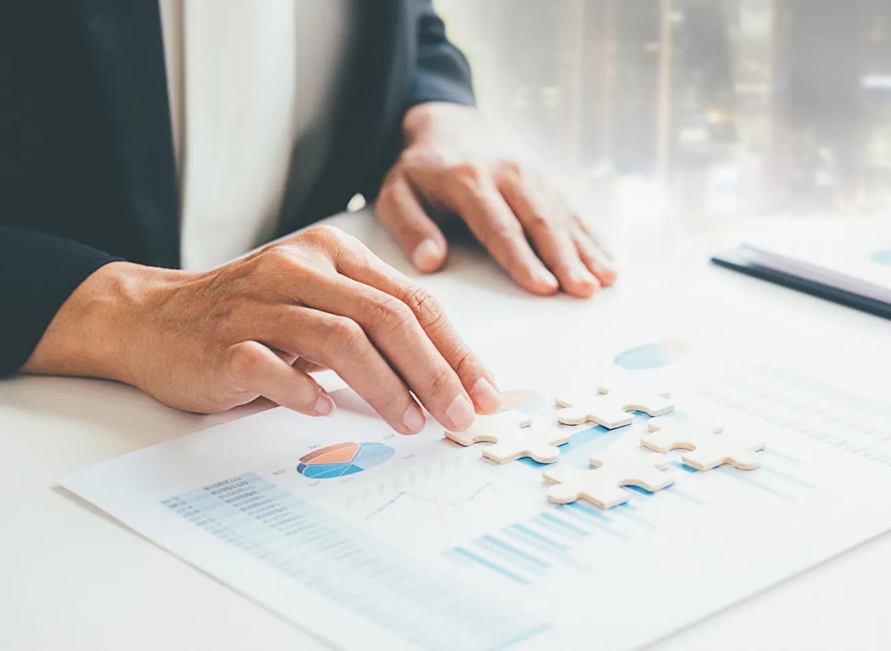 Hands fitting jigsaw puzzle pieces on business charts