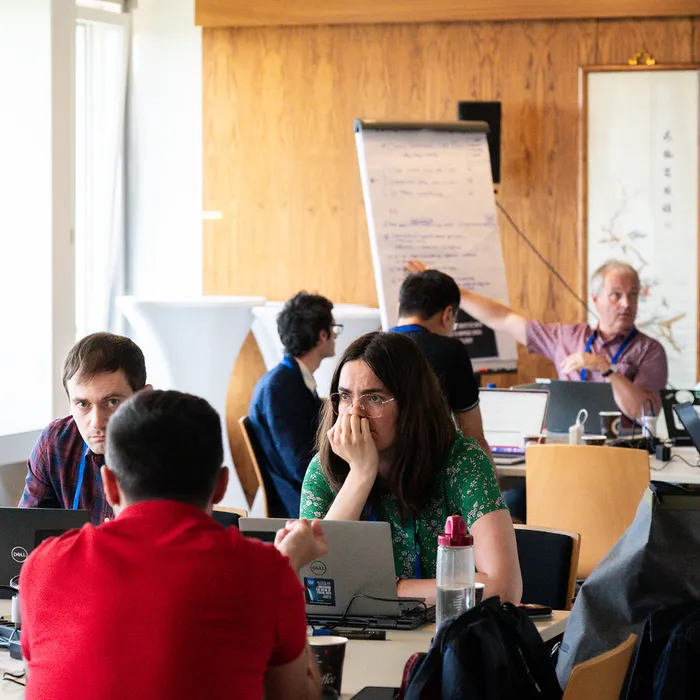 Teams working on laptops around tables during the hackathon
