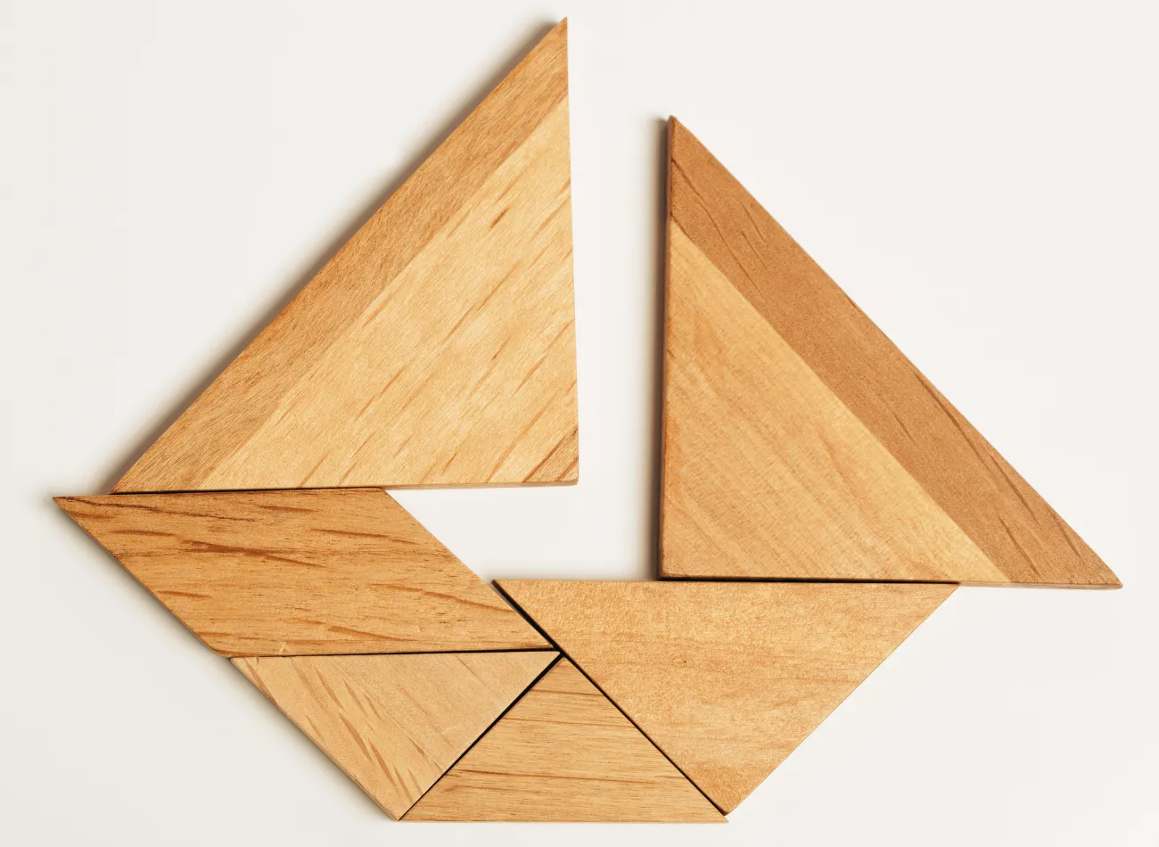 Wooden tangram pieces arranged into a sailboat