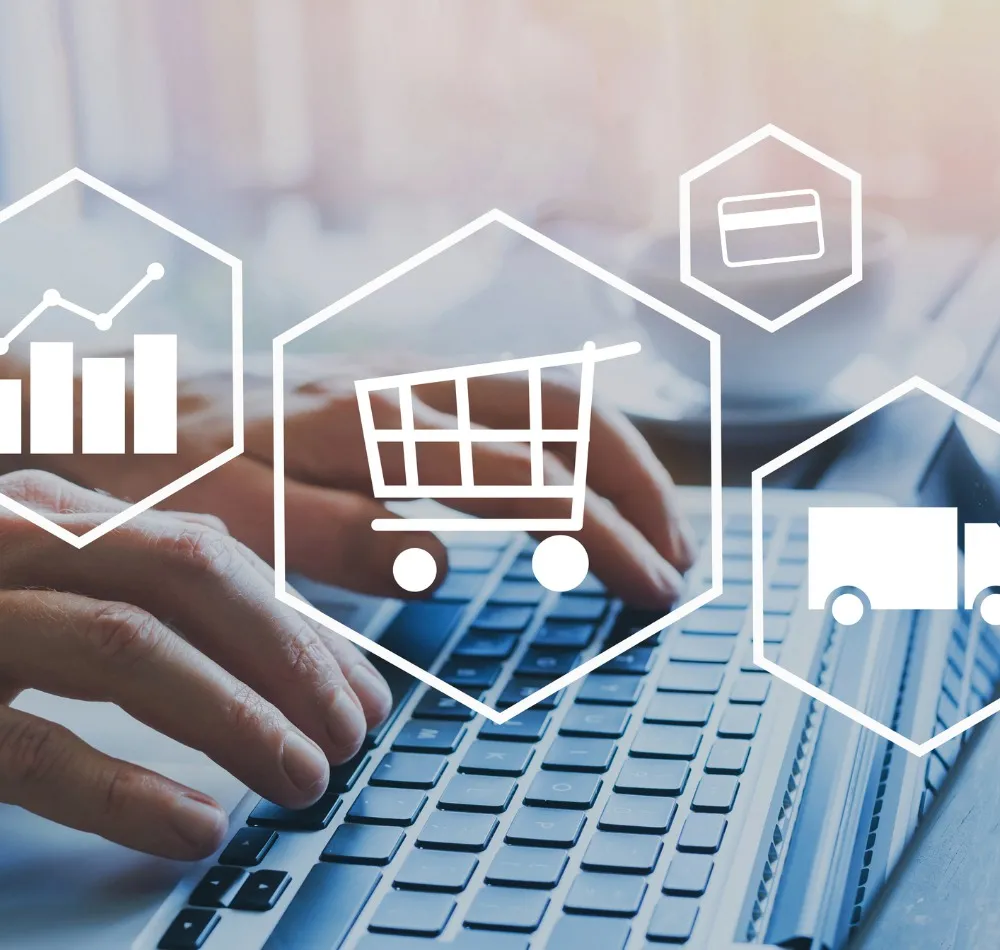 Hands typing on a laptop overlaid with e-commerce icons: a chart, shopping cart, payment card and delivery truck