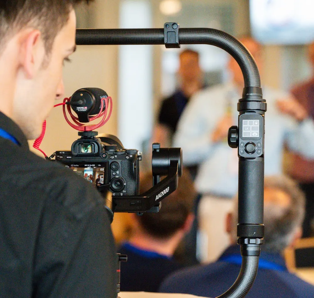 Videographer filming a conference session with a camera on a gimbal