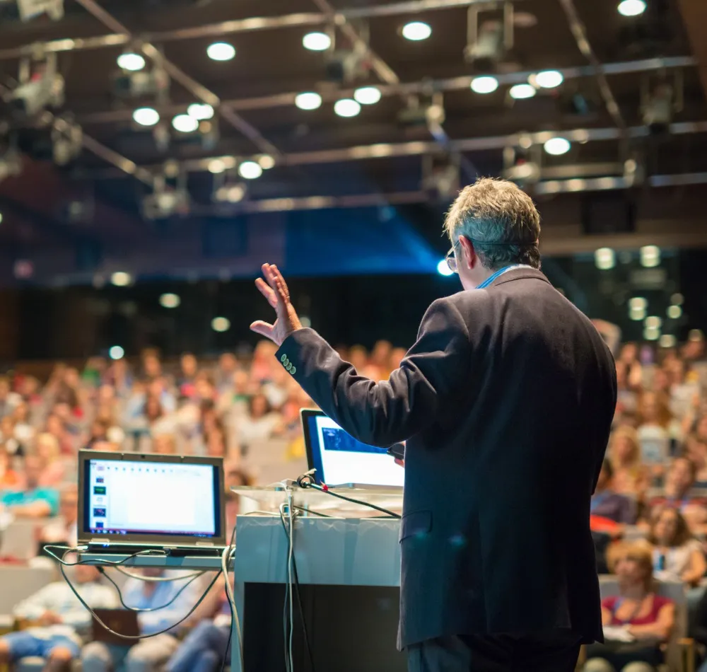 Speaker at a podium addressing a packed lecture hall