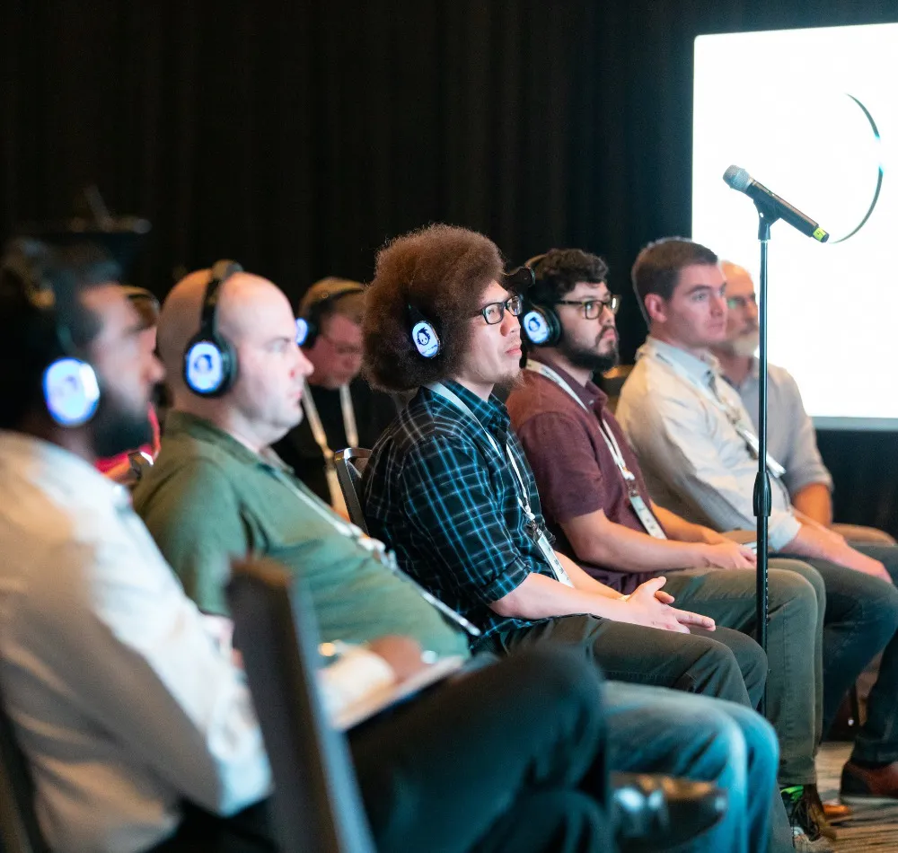 Audience members wearing headphones listening to a conference session
