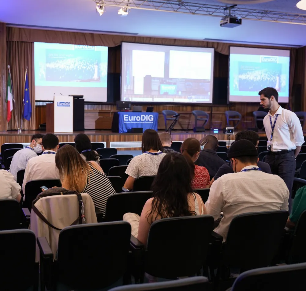 Audience seated in front of the EuroDIG stage and projection screens